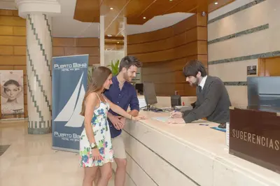 two men and a woman standing at a counter at Hotel Puerto Bahía & Spa in El Puerto de Santa María