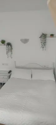 a bedroom with a white bed with a white bedspread at Hostal Restaurante La Giralda in Rota