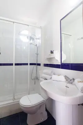 a white bathroom with a toilet and a sink at Hostal Restaurante La Giralda in Rota