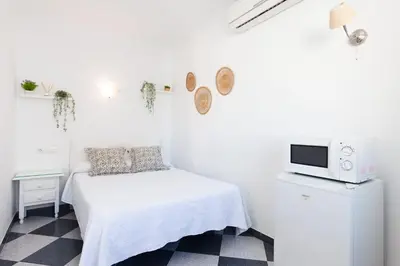 a white bedroom with a bed and a tv at Hostal Restaurante La Giralda in Rota