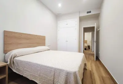 a white bedroom with a bed and a wooden floor at APARTAMENTOS SANLUCAR CASA A in Sanlúcar de Barrameda