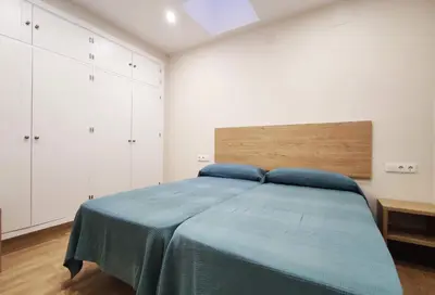 a bedroom with a bed with blue sheets and white cabinets at APARTAMENTOS SANLUCAR CASA B in Sanlúcar de Barrameda