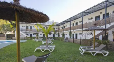 a group of chairs and umbrellas next to a building at Campomar Playa in El Puerto de Santa María