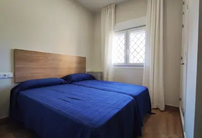 a bedroom with a blue bed and a window at APARTAMENTOS SANLUCAR CASA C in Sanlúcar de Barrameda