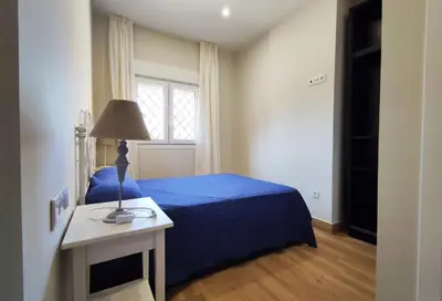 a bedroom with a blue bed and a window at APARTAMENTOS SANLUCAR CASA C in Sanlúcar de Barrameda