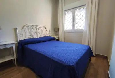 a bedroom with a blue bed and a window at APARTAMENTOS SANLUCAR CASA C in Sanlúcar de Barrameda