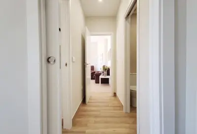 a hallway leading to a living room with white walls and wood floors at APARTAMENTOS SANLUCAR CASA D in Sanlúcar de Barrameda