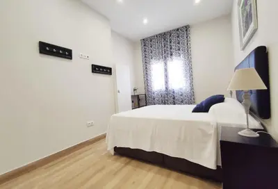 a white bedroom with a bed and a window at APARTAMENTOS SANLUCAR CASA D in Sanlúcar de Barrameda