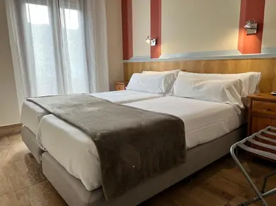 a bedroom with a large bed with white sheets and pillows at Hotel Pinomar in El Puerto de Santa María