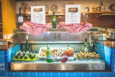 a display case in a restaurant with food and drinks at Playaballena in Costa Ballena