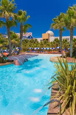 a swimming pool with palm trees and umbrellas at Playaballena in Costa Ballena
