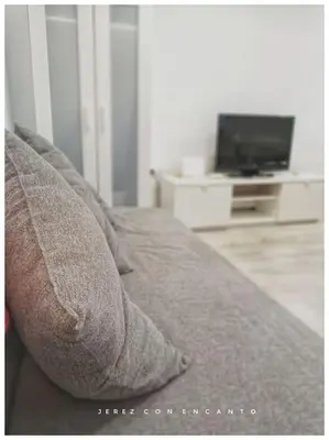 a couch with two pillows and a television in a room at Ático en pleno centro de Jerez sin ascensor in Jerez de la Frontera