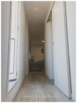 a hallway with a room with a couch and a window at Ático en pleno centro de Jerez sin ascensor in Jerez de la Frontera