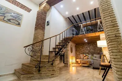 a spiral staircase in a living room with a brick wall at SH Casa de la Catedral. En el centro de la ciudad. in Cádiz