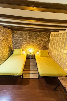 two beds in a room with a brick wall at SH Casa de la Catedral. En el centro de la ciudad. in Cádiz
