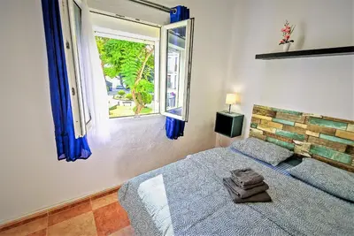 a bedroom with a bed with blue curtains and a window at Plaza Polvorista 4-Bedroom Apartment w Balcony in El Puerto de Santa María