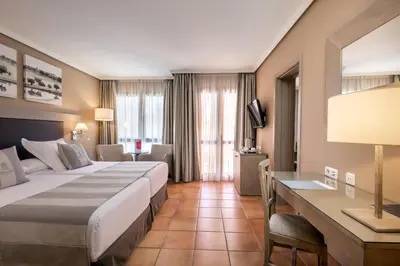 a hotel room with two beds and a desk at Barceló Montecastillo Golf in Jerez de la Frontera