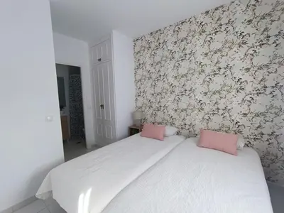 a bedroom with a white bed with pink pillows on it at Vistahermosa Palm in El Puerto de Santa María