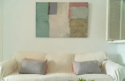 a white couch with two pillows sitting under a painting at Vistahermosa Palm in El Puerto de Santa María