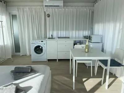 a kitchen and living room with a washing machine and a table at Ático Cádiz 360 in Cádiz