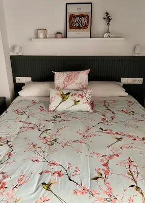 a bed with pink flowers on it with two pillows at Apartamento Duplex casa Palacio rehabilitado centro El Puerto in El Puerto de Santa María