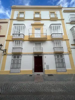 a yellow and white building with windows and a door at Apartamento Duplex casa Palacio rehabilitado centro El Puerto in El Puerto de Santa María