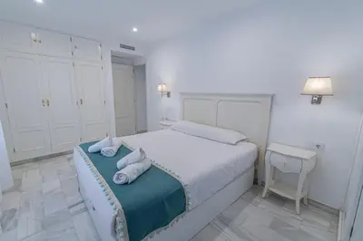 a white bedroom with a bed with towels on it at Apartamento El parador del boticario in Cádiz