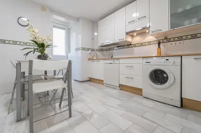 a kitchen with a table and a washing machine at Apartamento El parador del boticario in Cádiz