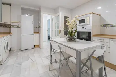 a kitchen with white appliances and a table with chairs at Apartamento El parador del boticario in Cádiz