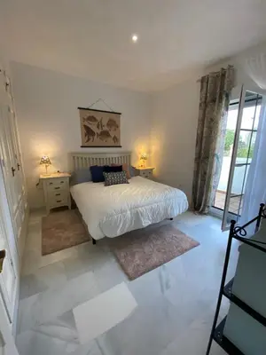 a bedroom with a bed and two tables and a window at Casa Rosa in Chiclana de la Frontera