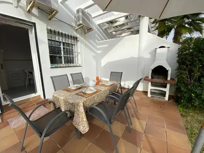 a patio with a table and chairs and a fireplace at Casa Rosa in Chiclana de la Frontera