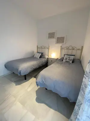 a bedroom with two beds and a lamp on a floor at Casa Rosa in Chiclana de la Frontera