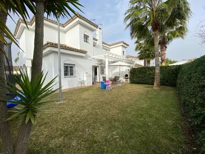 a white house with a yard with palm trees at Casa Rosa in Chiclana de la Frontera