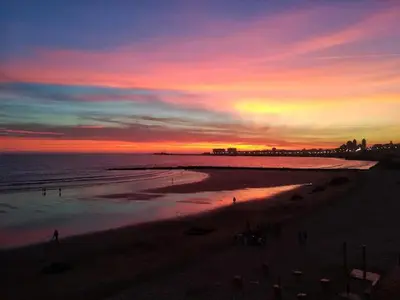 a sunset on a beach with people walking on the sand at Apartamento Cádiz Costa in Cádiz