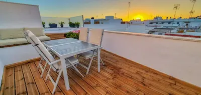 a table and two chairs on a balcony with the sunset at Penthouse with Jacuzzi, and garaje Grupo AC Gestion in Cádiz