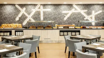 a restaurant with tables and chairs and a counter with food at Ilunion Calas de Conil in Conil de la Frontera