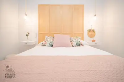 a bedroom with a large bed with a pink blanket at Apartamento Sanlúcar Sunset in Sanlúcar de Barrameda