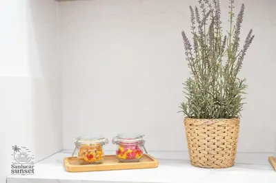 two glass jars and a vase with flowers on a counter at Apartamento Sanlúcar Sunset in Sanlúcar de Barrameda
