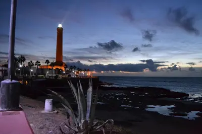 a lighthouse on a pier with the ocean at night at Brasilia in Chipiona