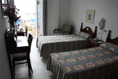 a hotel room with two beds and a table and a desk at Brasilia in Chipiona