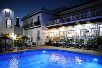 a swimming pool in front of a building at night at Brasilia in Chipiona