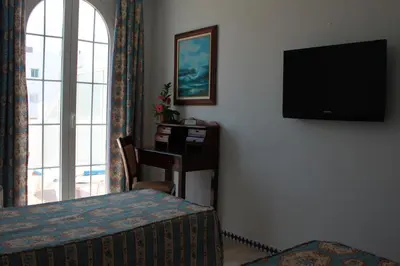 a bedroom with a bed and a television on a wall at Brasilia in Chipiona