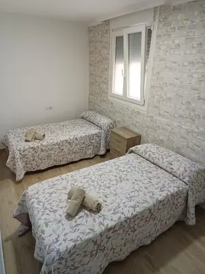 a bedroom with two beds and a window at Piso Avenida junto a la Playa in Cádiz