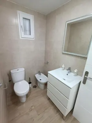 a white bathroom with a toilet and a sink at Piso Avenida junto a la Playa in Cádiz