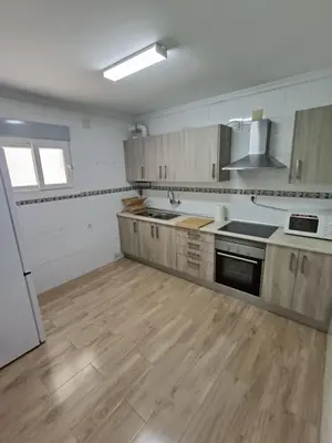 a large kitchen with wooden floors and stainless steel appliances at Piso Avenida junto a la Playa in Cádiz