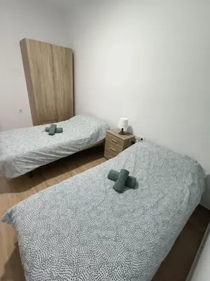 two beds in a room with two green crosses on them at Piso Avenida junto a la Playa in Cádiz
