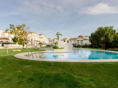 a large swimming pool in a yard with houses at Aparta-club la Barrosa 116 in Chiclana de la Frontera