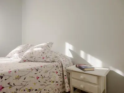a bedroom with a bed and a nightstand with a book at Aparta-club la Barrosa 116 in Chiclana de la Frontera