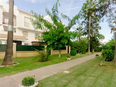 a garden with palm trees and a building at Aparta-club la Barrosa 116 in Chiclana de la Frontera