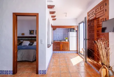 a hallway with a bed and a kitchen in a room at Apartamentos El Roqueo in Conil de la Frontera